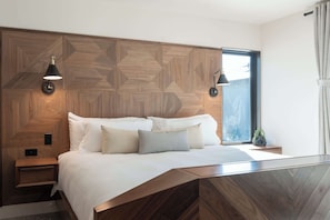 Ein modernes Schlafzimmer mit einem Kopfende mit geometrischem Muster, einem Bett mit vielen Kissen, Nachttischlampen und einem Fenster mit Vorhängen.