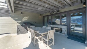 An outdoor patio with a table and chairs, a grill, and a view of a mountainous landscape. - Modern Lakefront Condo F1 + Pool - Wapato Chelan (Manson)