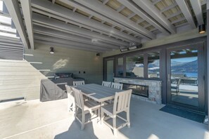 Eine Terrasse im Freien mit Tisch, Stühlen, einem Grill und Blick auf eine gebirgige Landschaft.