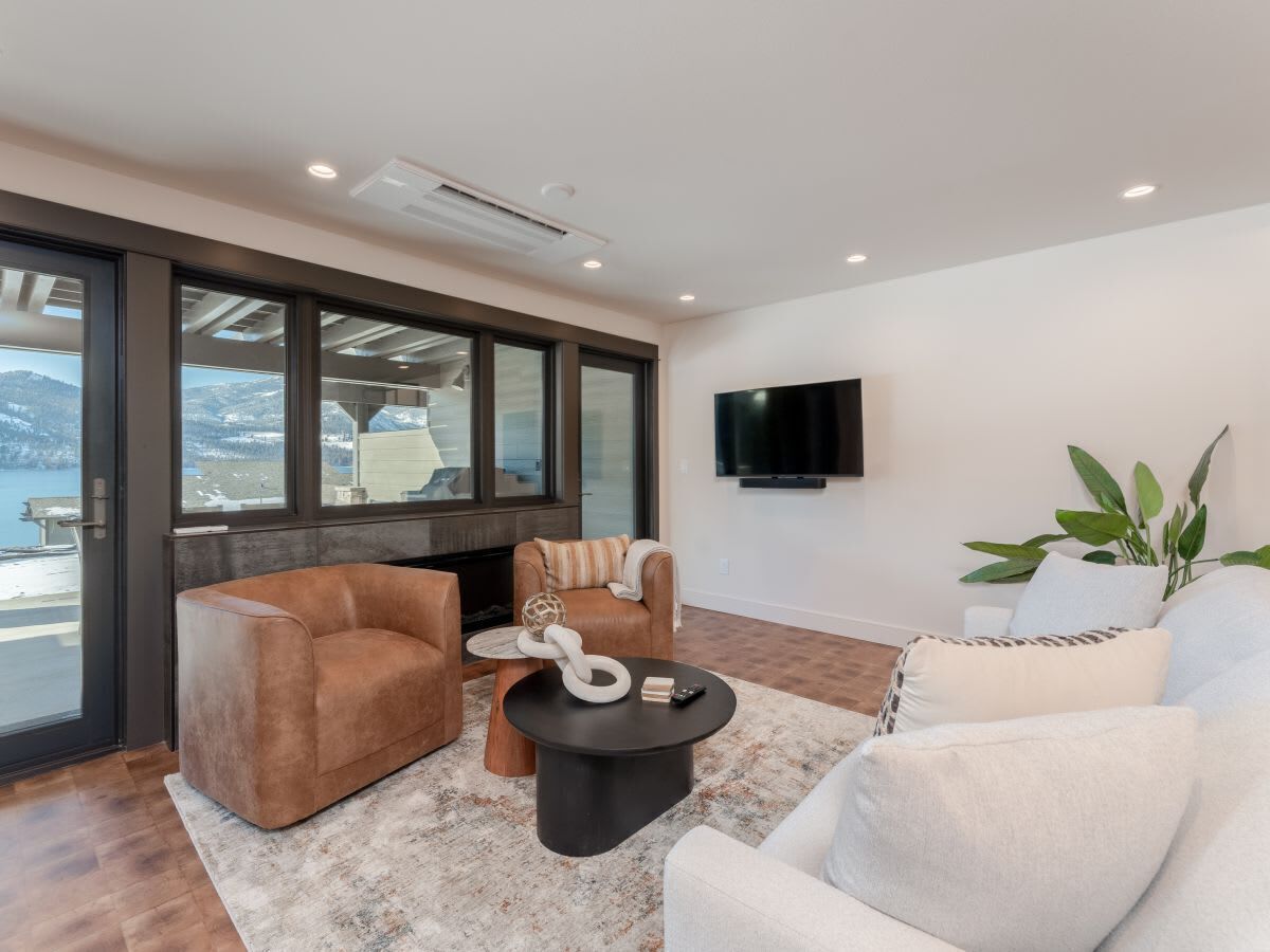 A modern living room with a sofa, armchairs, a coffee table, and a TV mounted on the wall.