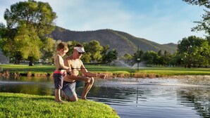 A man and a child fishing by a calm lake with a grassy bank and trees in the background. - Modern Lakefront Condo F1 + Pool - Wapato Chelan (Manson)