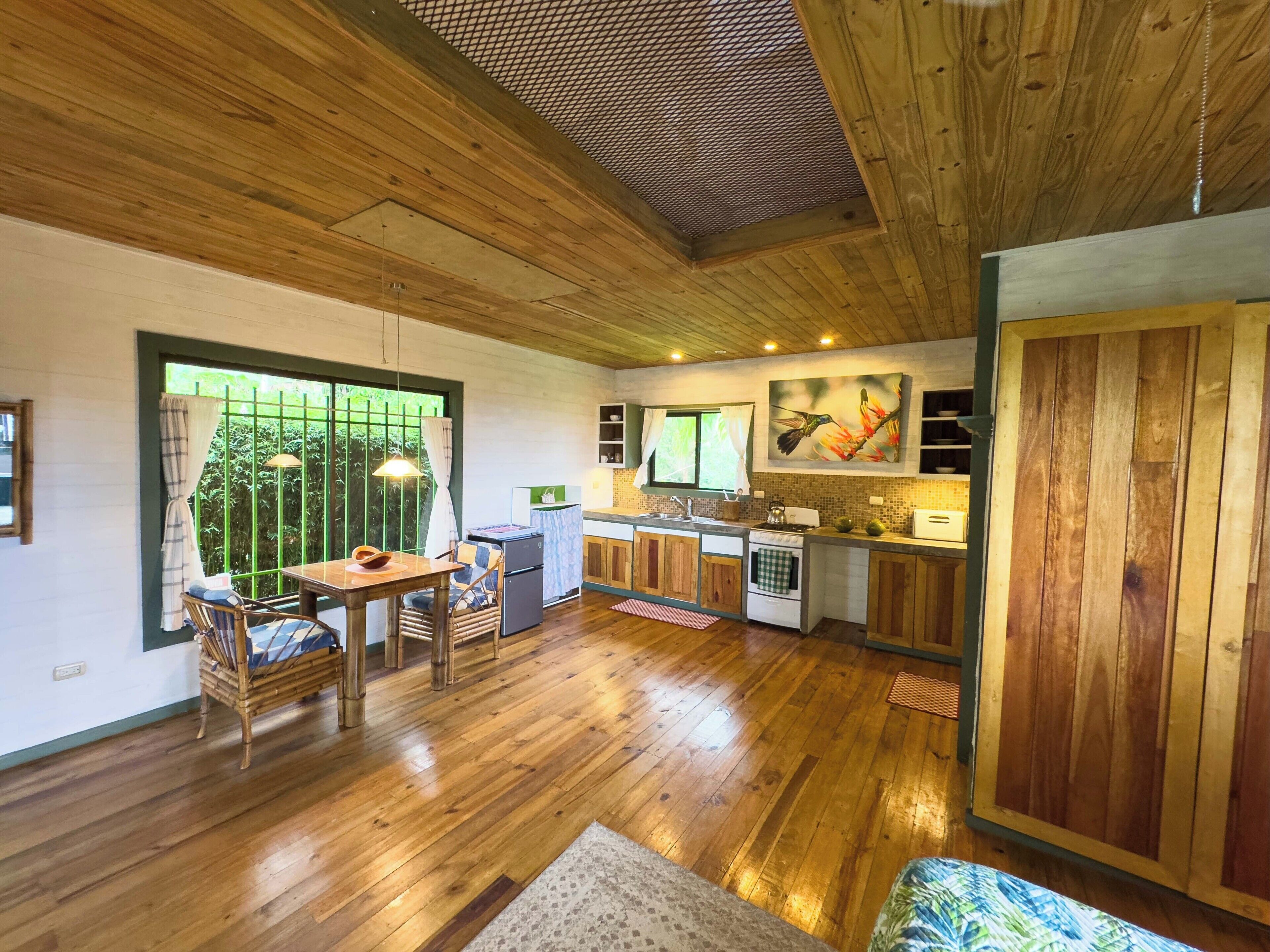 Une cuisine spacieuse avec des meubles en bois, un coin repas comprenant une table et des chaises, et une grande fenêtre donnant sur un paysage verdoyant.