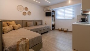 Una habitación moderna con cama, sofá, kitchenette y ventana con persianas.