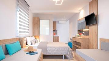 Habitación de hotel con dos camas, televisión, escritorio y kitchenette.