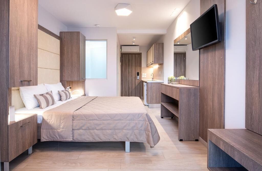 Une chambre moderne avec un grand lit, une armoire intégrée et un téléviseur à écran plat.