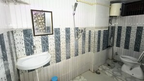 A bathroom with a white sink, a toilet, a shower, and a mirror. - Smriti Homestay (Varanasi)
