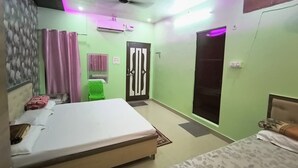 A bedroom with two beds, a green wall, a window, and a ceiling fan. - Smriti Homestay (Varanasi)