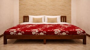 A bed with a wooden frame, a red floral bedspread, and two pillows. - Smriti Homestay (Varanasi)