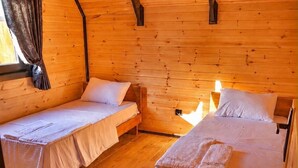 Una cabaña con dos camas individuales, piso de madera y techo inclinado.