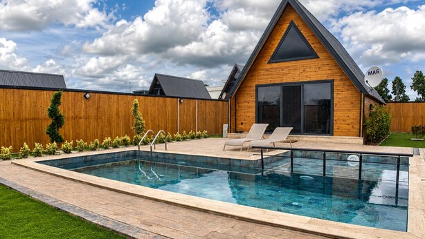Una casa moderna con piscina, terraza de madera y antena parabólica.
