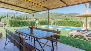 An outdoor patio with a wooden table and benches, a pool, and a view of a mountainous landscape. - Pollensa Mountain View Villa (Pollença)