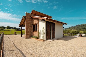 A small building with a sloped roof, a brick facade, and a gravel driveway.
