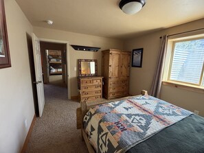 Een slaapkamer met een bed, een kaptafel en een raam met gordijnen.