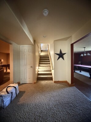 A carpeted hallway with a staircase leading to a room with a billiards table. - NEW LISTING!  Peaceful 4-bedroom home in Big Sky ready for your next adventure. (Big Sky)