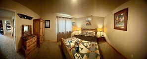A hotel room with a bed, a dresser, a mirror, a nightstand with lamps, and a painting on the wall. - NEW LISTING!  Peaceful 4-bedroom home in Big Sky ready for your next adventure. (Big Sky)