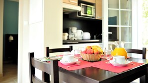 A dining table set with plates, glasses, a fruit basket, and a pitcher of orange juice.