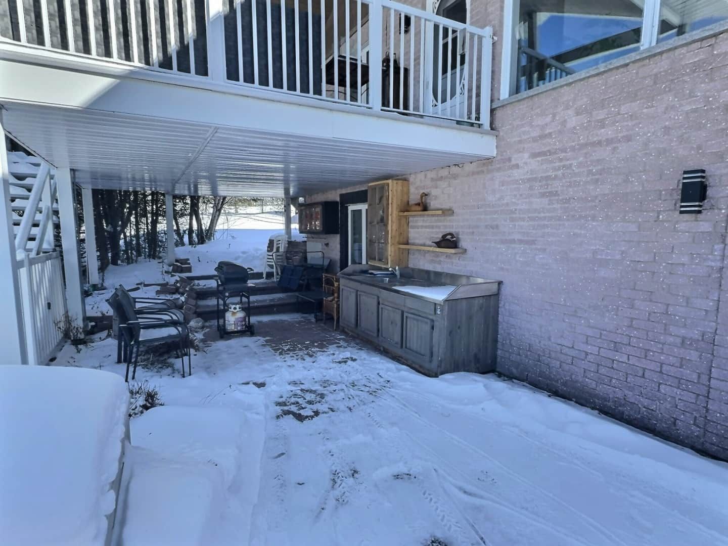 A covered outdoor area with a kitchen, seating, and a view of the backyard.