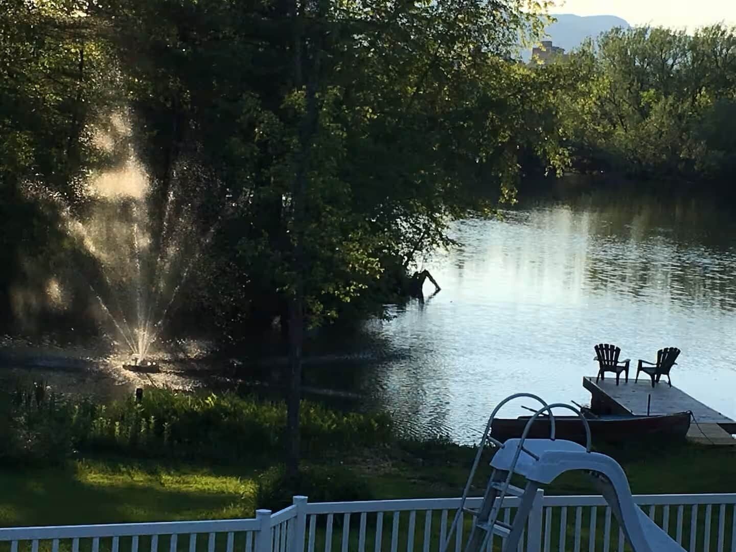A lakeside view with a dock, chairs, and a ladder.