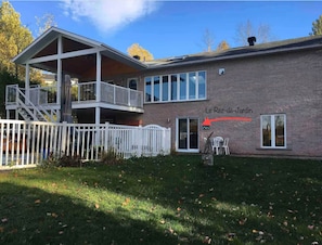 A two-story building with a balcony, a brick exterior, and a sign reading 'Le Rez-de-Jardin'. - Bord de l’eau Magog : Le Rez-de-Jardin (Magog)