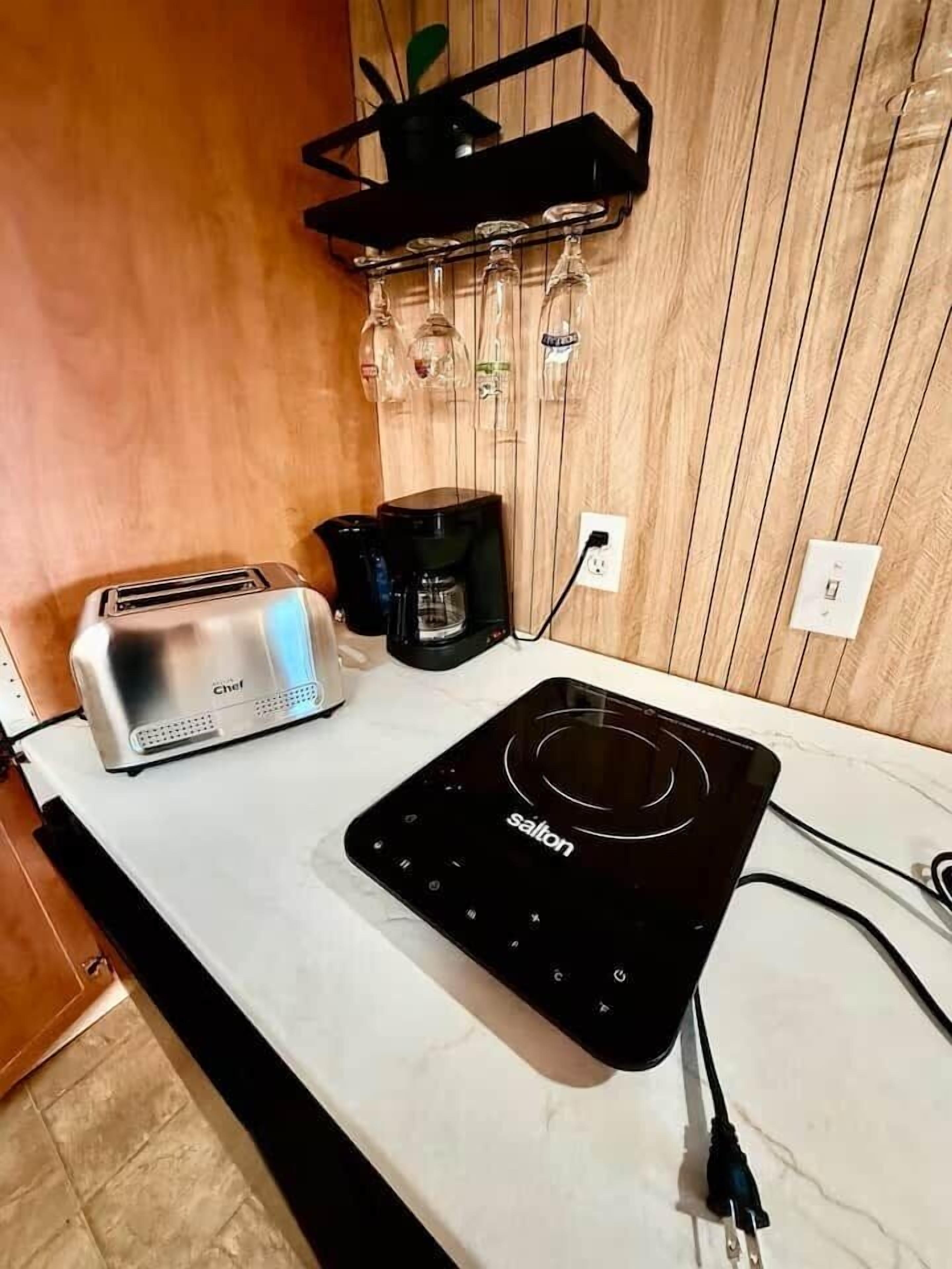 Eine Küche mit einem Toaster, einer Kaffeemaschine und einer schwarzen Induktionskochplatte.
