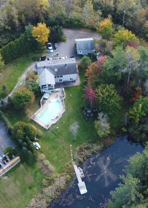 Ein Luftbild eines Wohnhauses mit Swimmingpool, Anlegesteg und Boot.