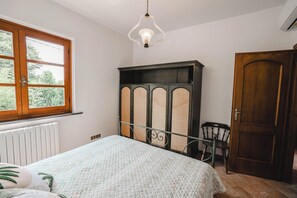 Ein Schlafzimmer mit Bett, Heizkörper, Kleiderschrank, Stuhl und Fenster.