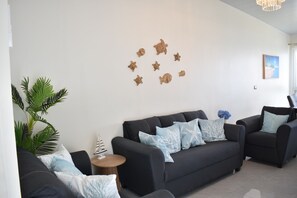 A modern living room with a dark sofa, two armchairs, and a small round table.