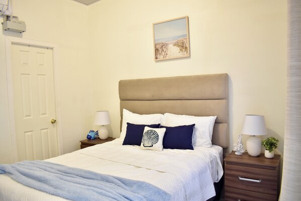A bedroom with a bed, bedside tables, a lamp, a picture on the wall, and a door.