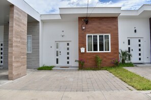 A modern building with numbered doors, a window, and a small garden area.