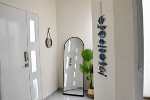 A hallway with a white door, a large mirror, and a wall-mounted fish decoration.