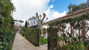 A stone pathway leading to a house with a fenced garden.