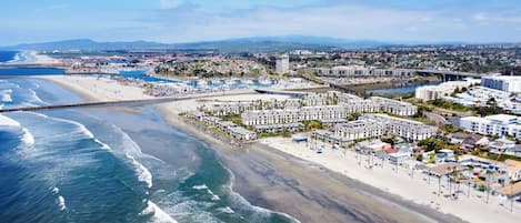 An aerial view of a coastal resort area with beachfront hotels, a marina, and a beach.