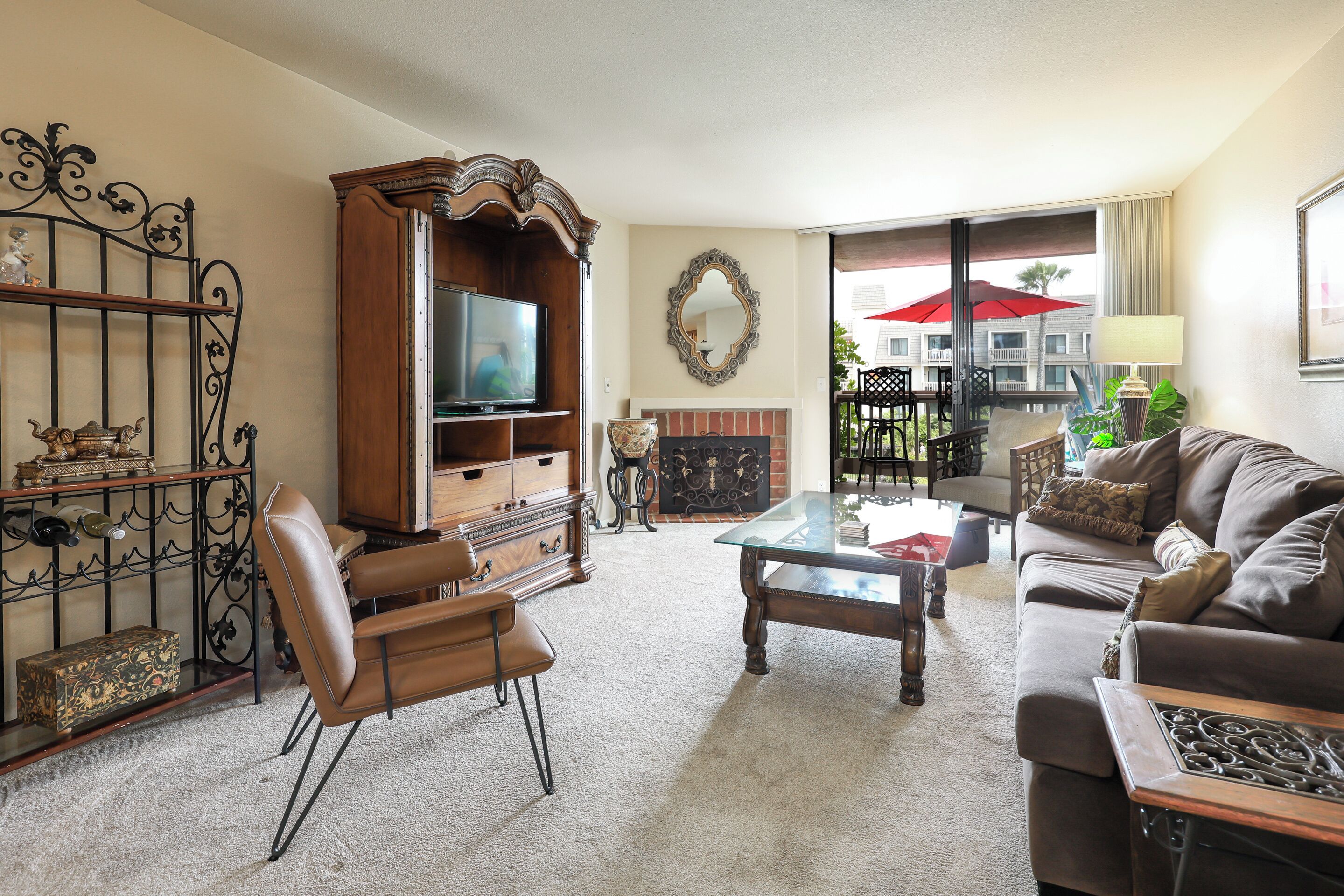 A living room with a television, leather chairs, a glass coffee table, and a fireplace.