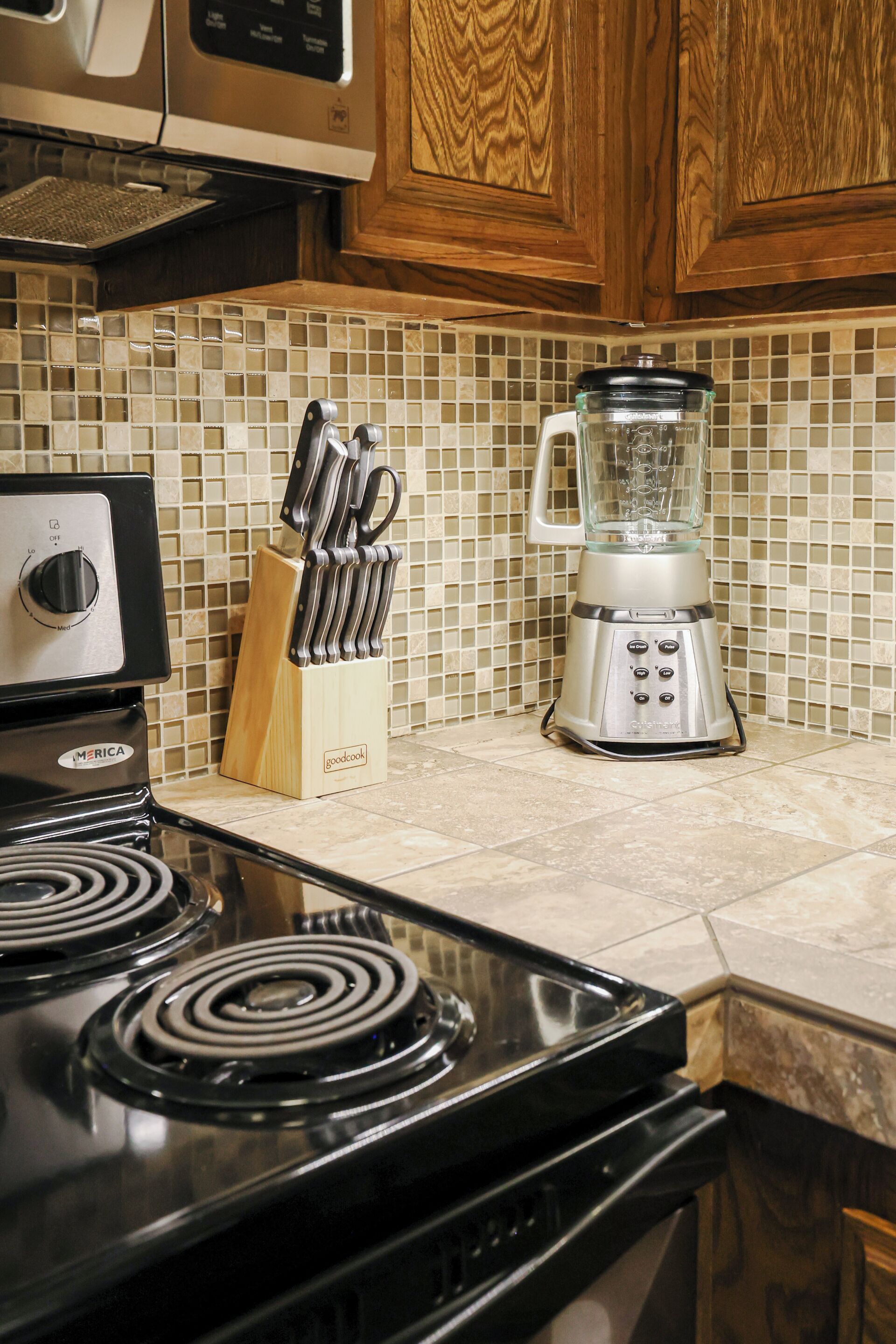 A kitchen with a black stove, a blender, and a knife block.