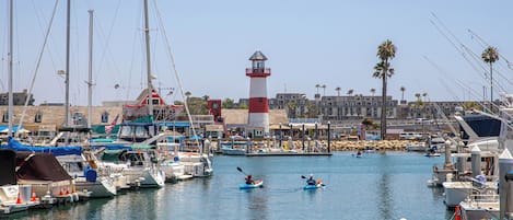 Un puerto deportivo con barcos, un faro y un edificio con techo rojo.
