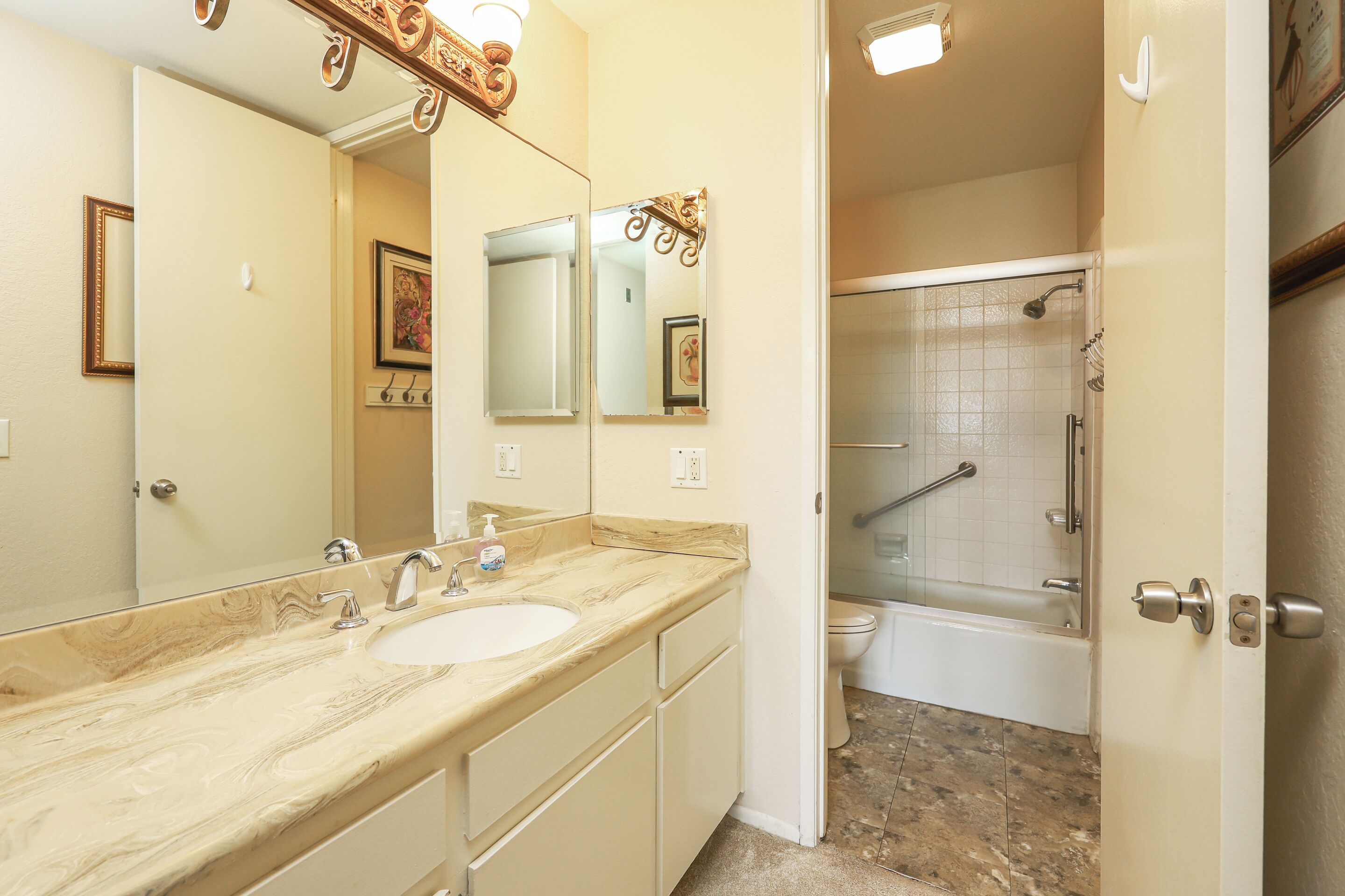A bathroom with a marble sink, a large mirror, a shower with a glass door, and a toilet.