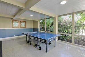 A ping pong table in a room with large windows, a ceiling with recessed lighting, and a wall with framed pictures. - Tropical Beach 1br/1ba Retreat at North Coast Village (Oceanside)