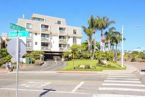 A multi-story building with balconies, a crosswalk, and palm trees. - Harbor and Ocean View Coastal Retreat Walk to Beach & Marina (Oceanside)