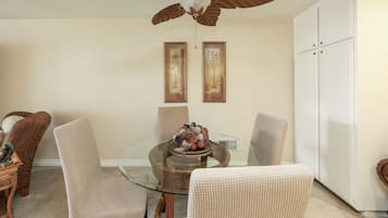 Un coin repas avec une table en verre, des chaises en osier et un ventilateur de plafond.