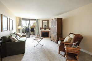 A living room with a sofa, a chair, a table, and a fireplace. - Bahama Breezes (Oceanside)