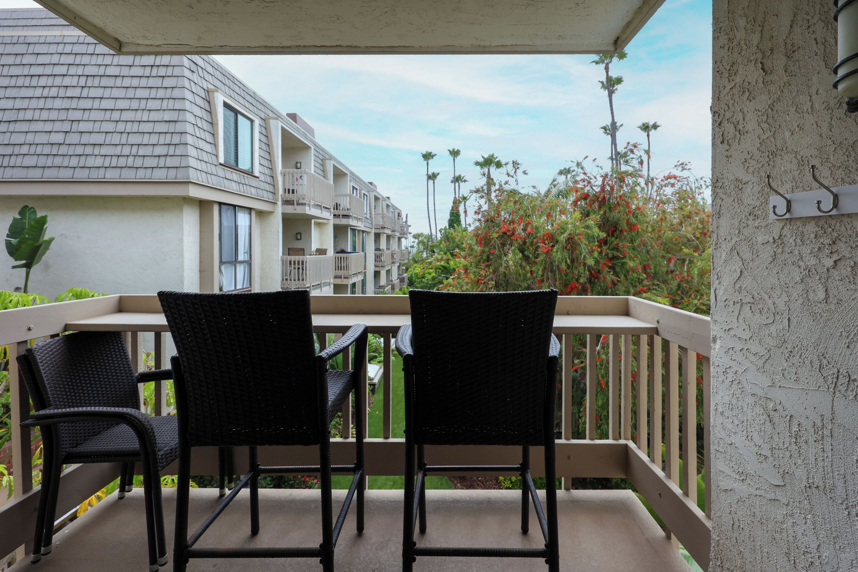 A balcony with two wicker chairs, a table, and a railing.