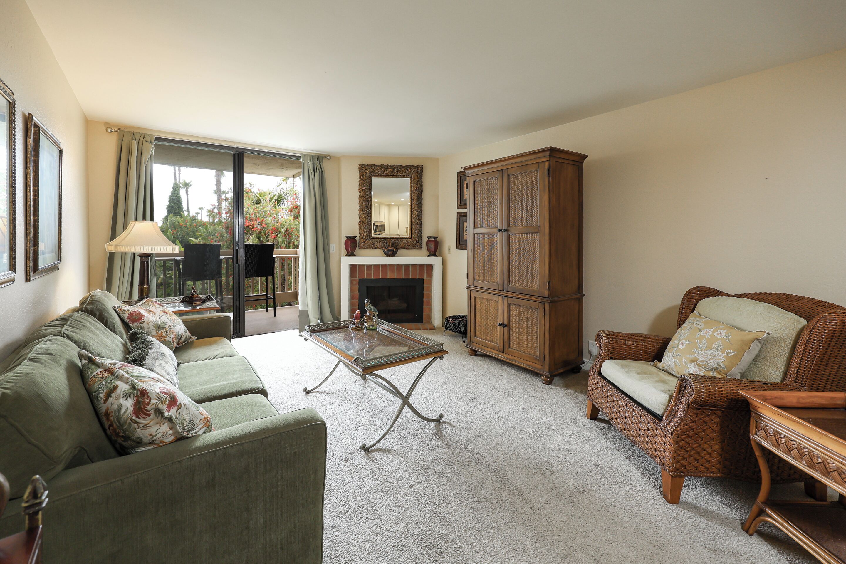 A living room with a sofa, armchair, fireplace, and a cabinet.
