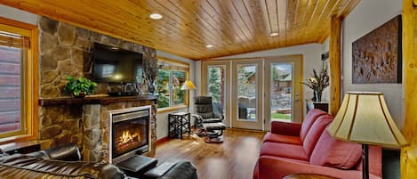 A cozy living room with a stone fireplace, leather sofas, and a flat-screen TV.