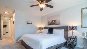 A bedroom with a bed, a ceiling fan, a nightstand with a lamp, and a wall-mounted TV. - Beautiful 2bd/2ba Luxury Cottage Unit With an Oceanview (Oceanside)