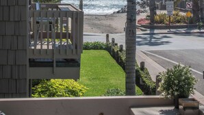 A beachfront property with a wooden deck, a view of the ocean, palm trees, and a 'Do Not Enter' sign. - Beautiful 2bd/2ba Luxury Cottage Unit With an Oceanview (Oceanside)