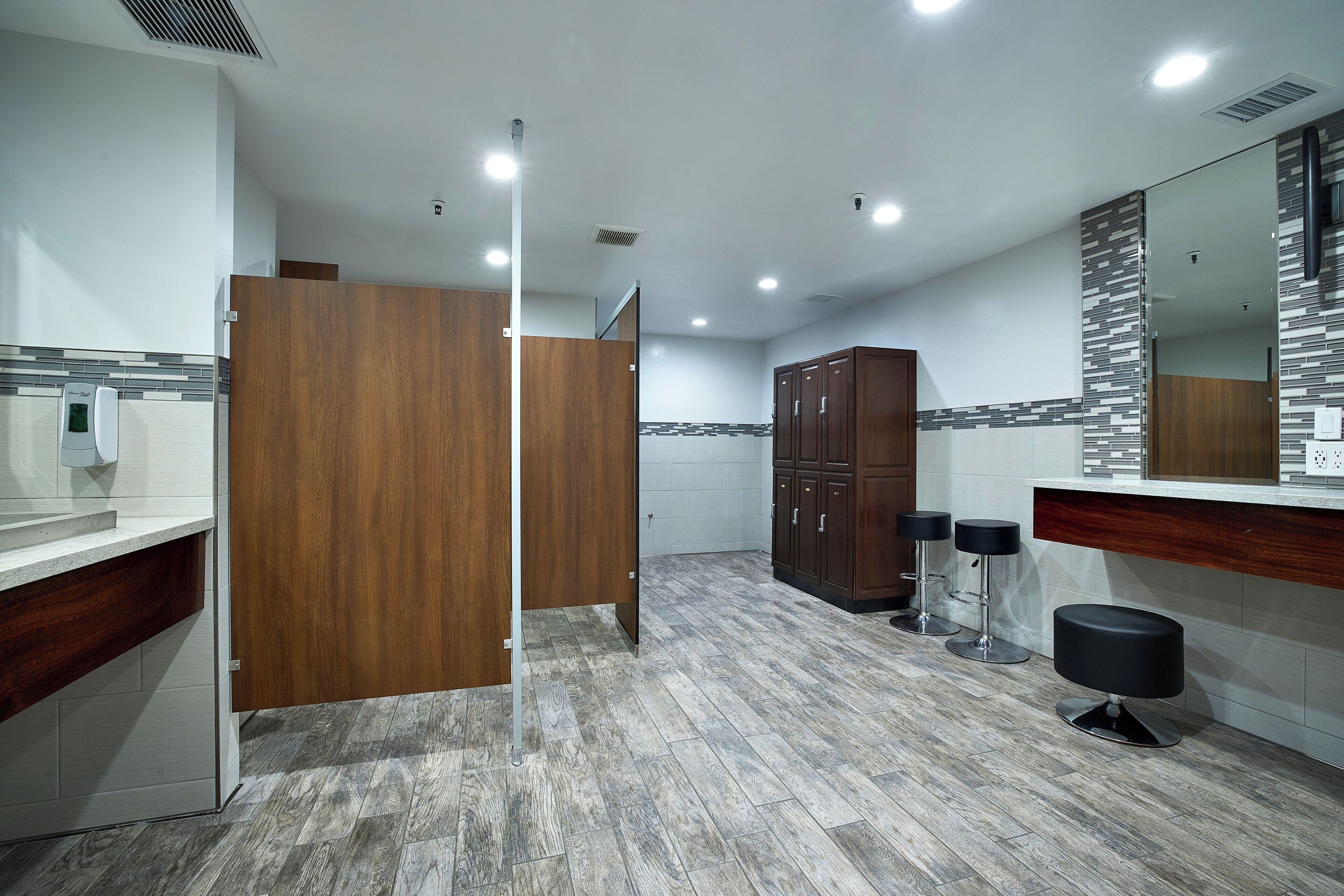 Ein modernes Badezimmer mit einer Holzwand, einem großen Spiegel und einem Barhocker.