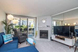 Ein modernes Wohnzimmer mit Kamin, einem großen Flachbildfernseher und einem Balkon mit Blick auf die Stadt.