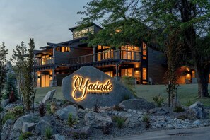 A modern multi-story hotel with a prominent rock sign in front, surrounded by landscaped rocks and plants. - Romantic Lakefront Condo F5 + Pool - Wapato Chelan (Manson)