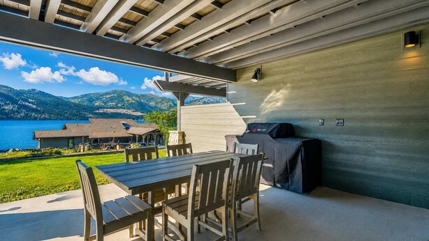 An outdoor patio with a table and chairs, a grill, and a view of a lake and mountains. - Romantic Lakefront Condo F5 + Pool - Wapato Chelan (Manson)
