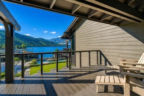 A wooden deck with a view of a lake and mountains, a railing, and a chair. - Romantic Lakefront Condo F5 + Pool - Wapato Chelan (Manson)